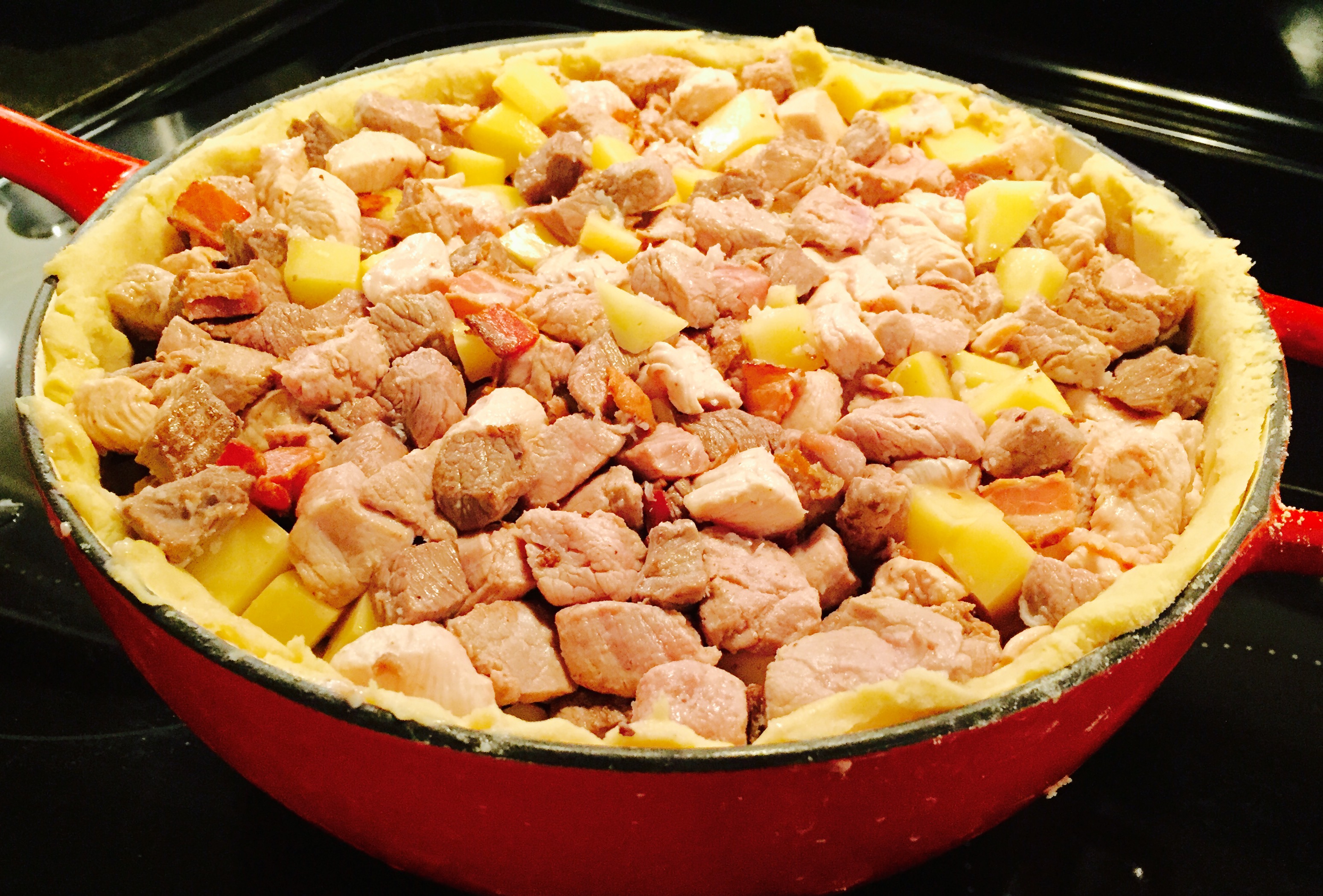 Braised beef pork and chicken in a massive pie shell lined Dutch oven ready to be topped up with wine and broth then covered ... crazy
