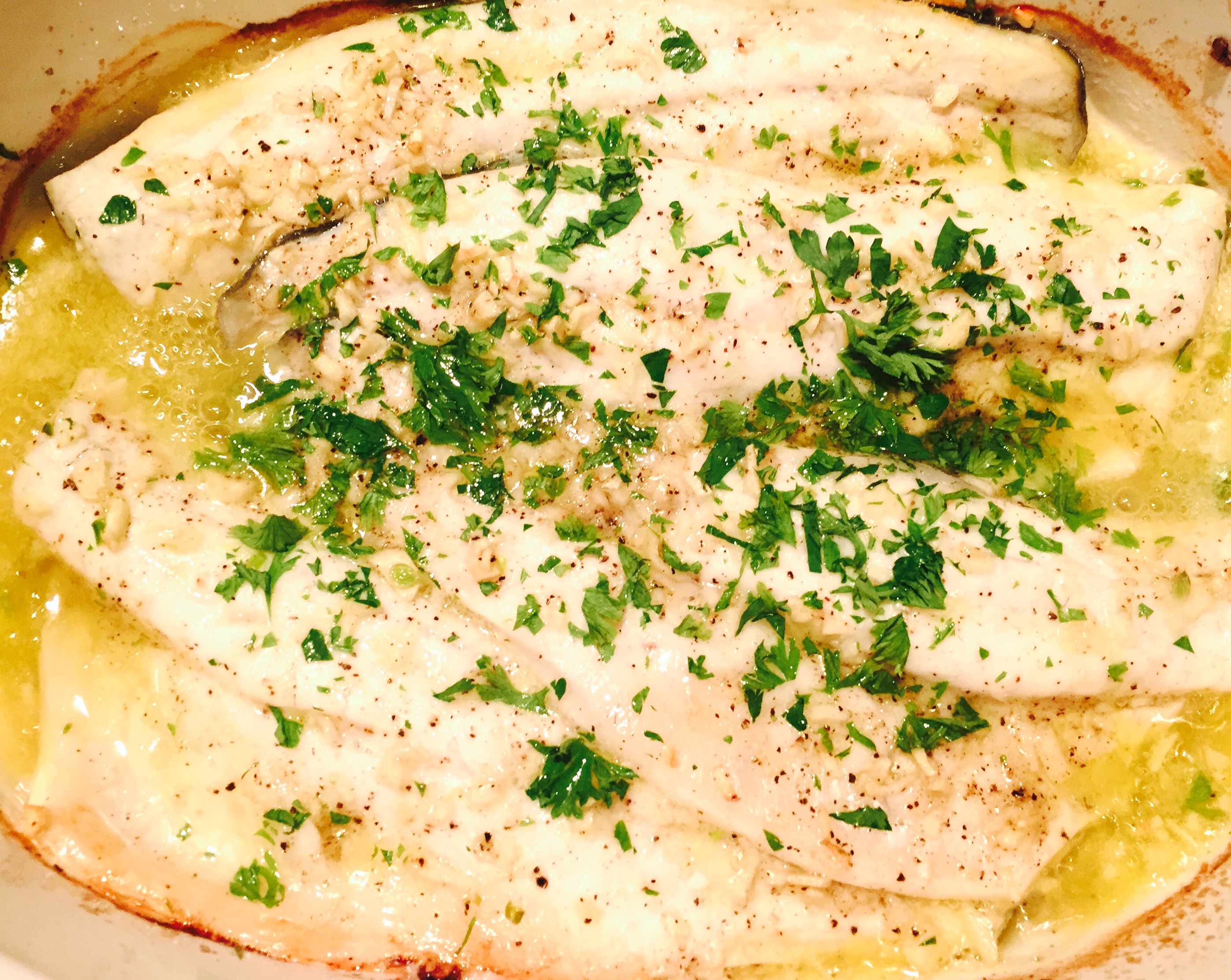 Baked sea bass with lemon butter, fresh garlic and chopped parsley