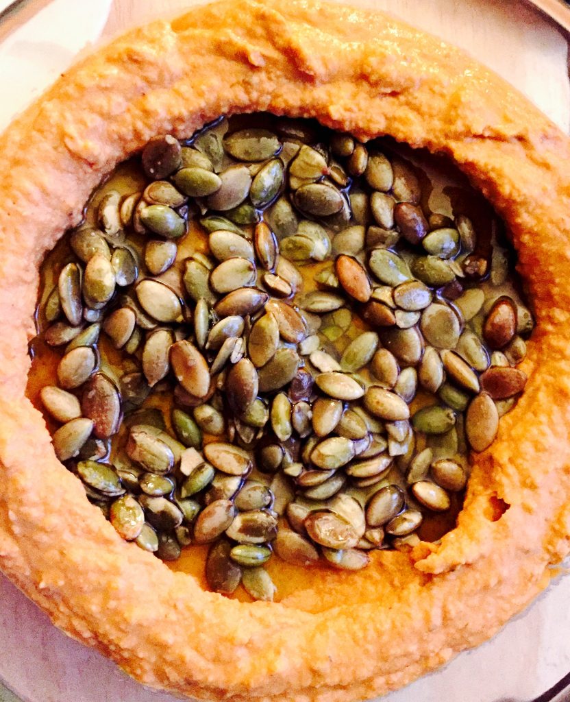 Some delicious homemade sun dried tomato hummus with roasted pumpkin seeds ready for snacking