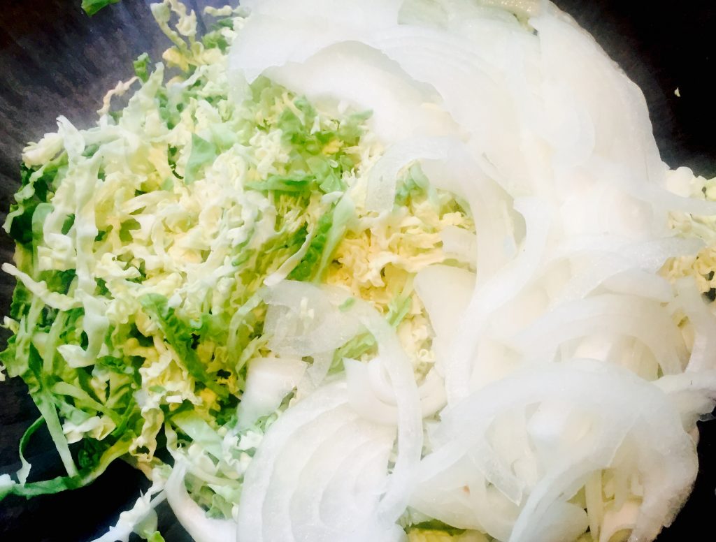 Some thinly sliced curly cabbage and onions in a tangy vinaigrette