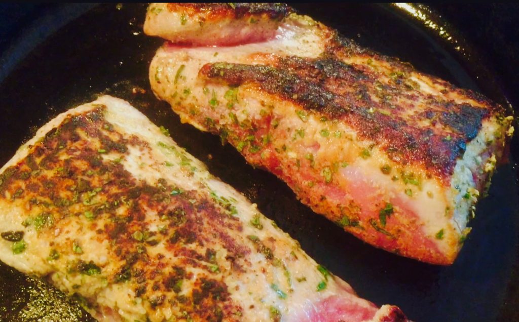 Pork tenderloin in a fresh herb rub, seared in a cast iron skillet and ready for the oven