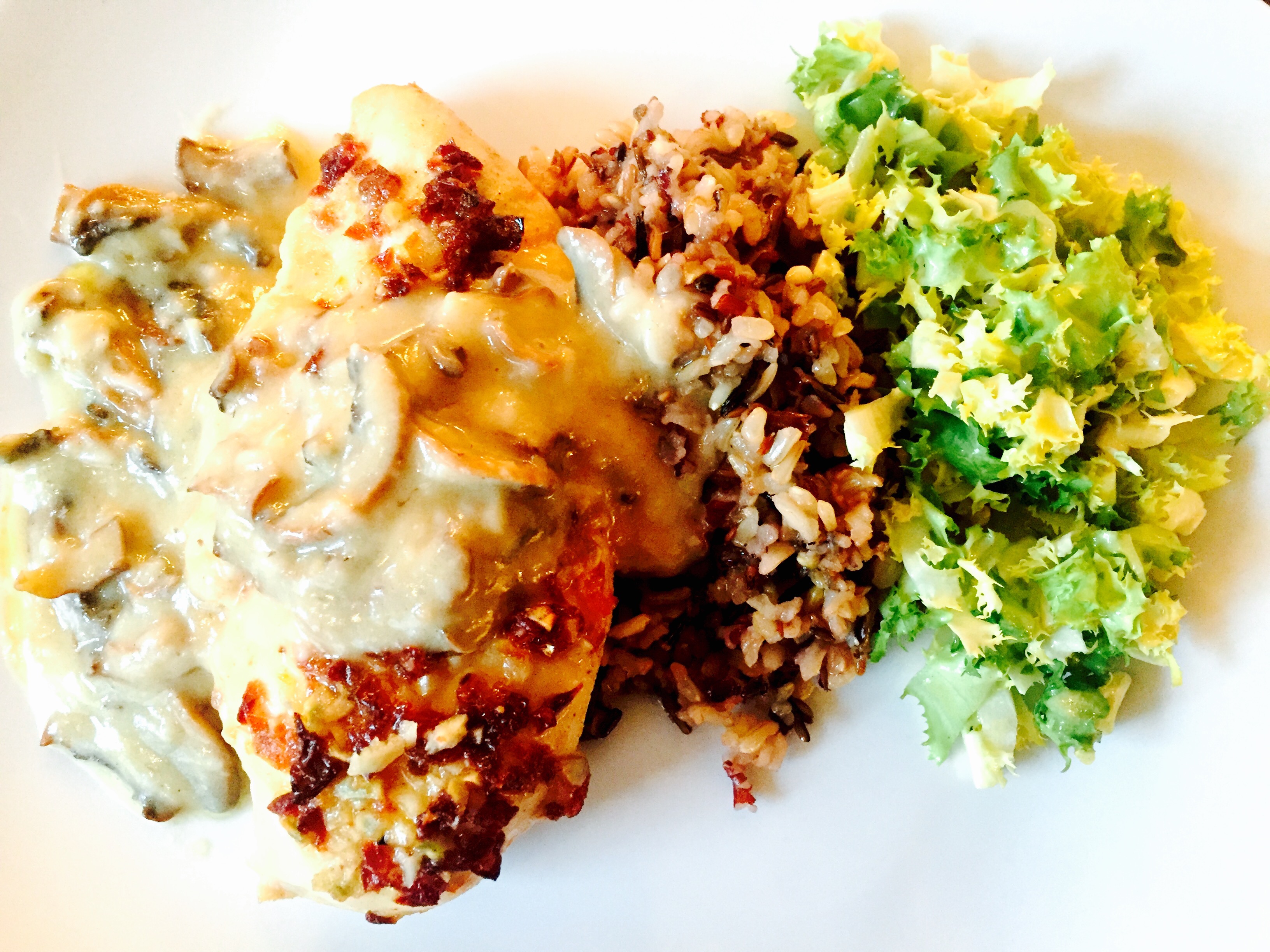 Roasted chicken breast in creamy mushroom sauce with wild rice and frisée salad